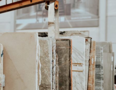 Vertical shot of marble and granite slabs with a construction hook indoors.
